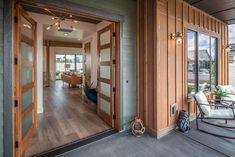 an open door leading to a living room and dining area with wood paneling on the walls