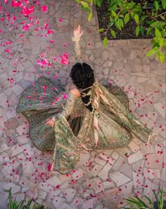 a woman in an elaborate dress is throwing petals into the air with her arms up