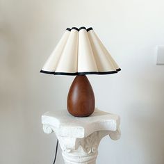 a table lamp sitting on top of a white pedestal next to a light switch and wall