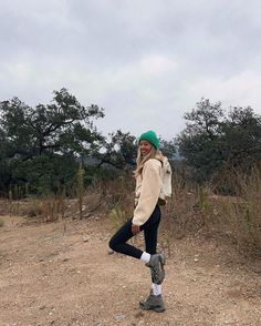 a woman standing on top of a dirt field next to a green frisbee