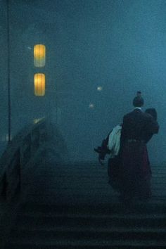 two people are walking up some stairs in the foggy night with their backpacks on