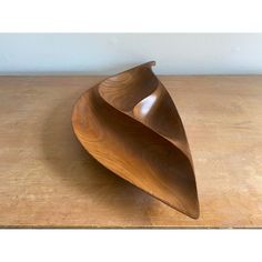 a wooden bowl sitting on top of a table next to a white wall and wood floor