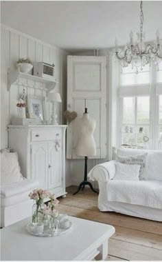 a living room with white furniture and chandelier