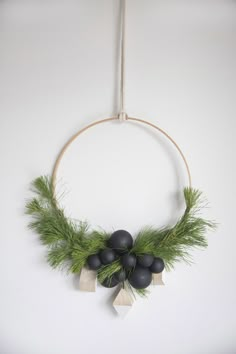 a wreath hanging on the wall with black balls and greenery