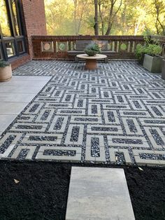 an outdoor area with black and white tiles on the ground, trees in the background