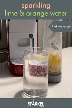 a glass filled with water sitting on top of a counter next to a blender