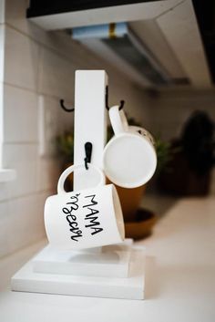 two mugs are sitting on top of a stand in the kitchen, one is upside down