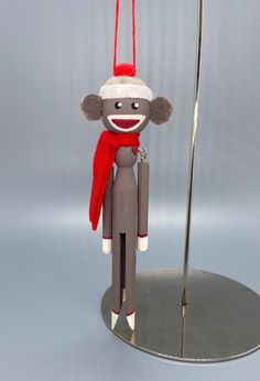 a toy monkey with a santa hat and scarf hanging from it's back on a metal stand