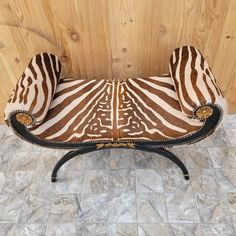 a zebra print bench sitting on top of a tile floor next to a wooden wall