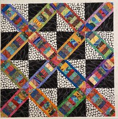 a black and white quilt with different colored strips on the front, along with an abstract design