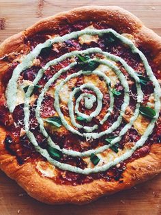 a pizza topped with spinach and sauce on top of a wooden cutting board next to a knife