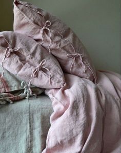 a bed with pink linens and pillows on it