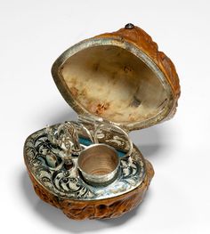 an old silver and wood box sitting on top of a white surface with the lid open