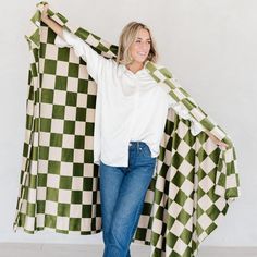 a woman holding up a green and white checkerboard blanket in front of her