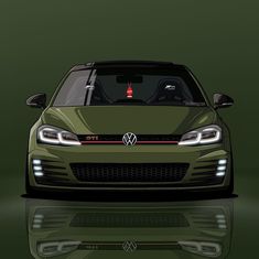 the front end of a green car with its hood up and lights on, reflecting in water