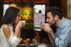 a man and woman sitting at a table drinking coffee