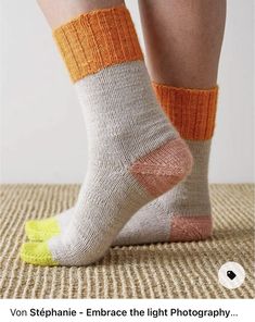 the legs of a person wearing socks with orange and white stripes on them, standing on a rug