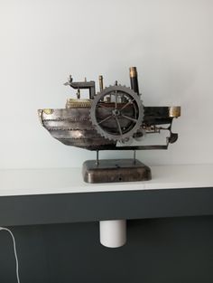 an old clock sitting on top of a white shelf next to a light bulb and plugged in