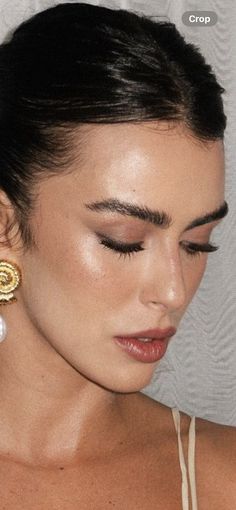 a close up of a woman wearing large gold and white earrings with pearls on her ear