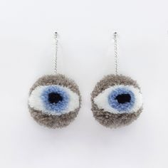 two pairs of blue and grey eyeball earrings hanging from chains on a white surface