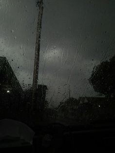 rain is falling on the windshield of a car as it sits in front of a building