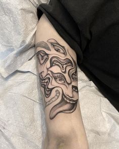 a person with a tattoo on their arm that has an image of two faces in the middle