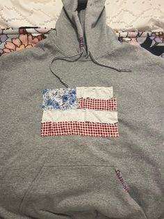 a gray hoodie with an american flag patch on the front and blue flowers on the back