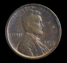 a close up of a coin on a black background with the image of a man in a suit and tie