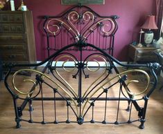 a metal bed frame with ornate designs on the headboard and foot board, against a pink wall