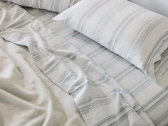 a bed with two pillows on top of it next to a pillow case and blanket