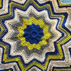 a blue and yellow crocheted blanket with a star design on the center is shown