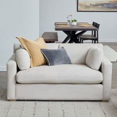 a living room with a couch, table and chairs next to each other in front of a painting on the wall