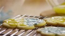 some cookies are cooling on a rack with yellow icing and blue frosting around them