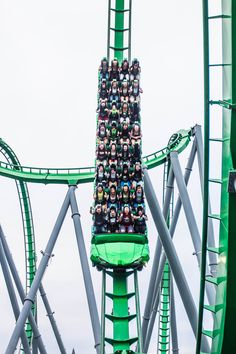 the roller coaster is full of people on it's back and green seat covers