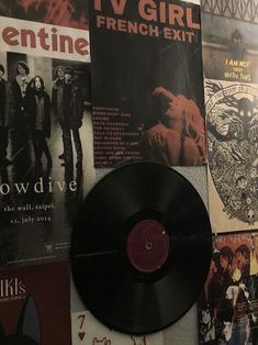 a black vinyl record sitting on top of a wall covered in posters and other items