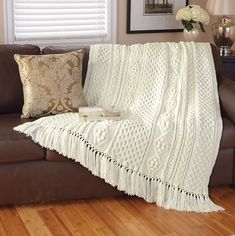 a white crocheted blanket sitting on top of a brown couch