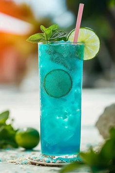 a blue drink with lime and mint garnish