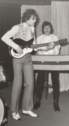 an old black and white photo of two people playing guitars