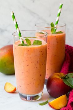 two glasses filled with peach smoothie next to fruit