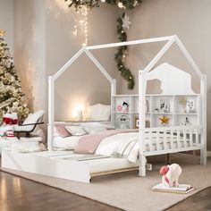 a white doll house bed sitting on top of a wooden floor next to a christmas tree