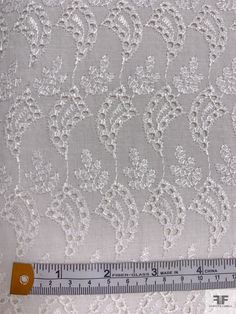 a ruler is next to a white lace fabric