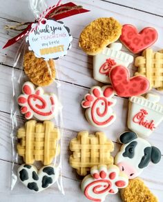 decorated cookies in the shape of waffles and farm animals on a white wooden table