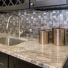 a kitchen counter top with two copper canisters and a sink in front of it