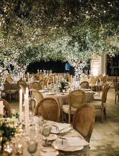 an outdoor dining area with tables, chairs and candles lit up at the end of each table