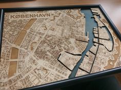 a wooden map of the city of kobenahn on display in a black frame