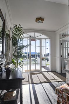 the sun shines in through an open door into a living room with large windows