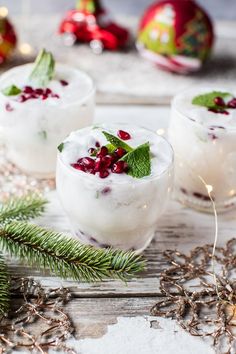 two glasses filled with ice and garnished with pomegranates on a wooden table