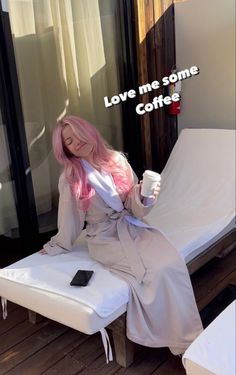 a woman with pink hair is sitting on a white chair and holding a coffee cup