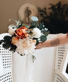 a person holding a bouquet of flowers in their hand while sitting on a white chair