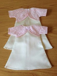 two white and pink dresses sitting on top of a wooden table